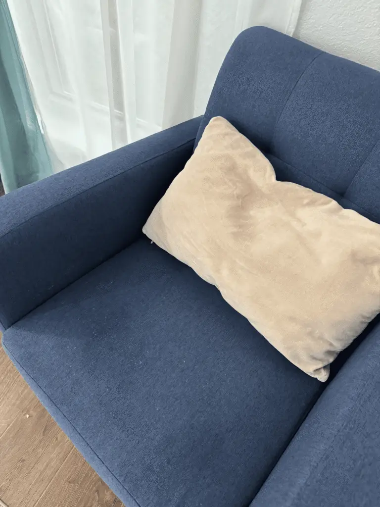 Blue fabric armchair with beige throw pillow