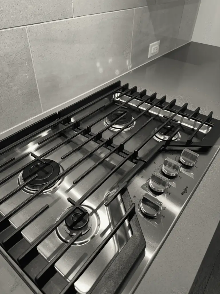 Clean stainless steel Whirlpool 5-burner gas cooktop with gray tile backsplash